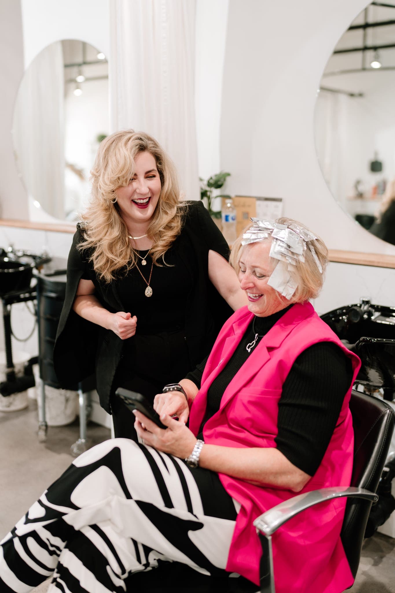 Stylist and client laughing together during a colour service at Lustre of Pearl