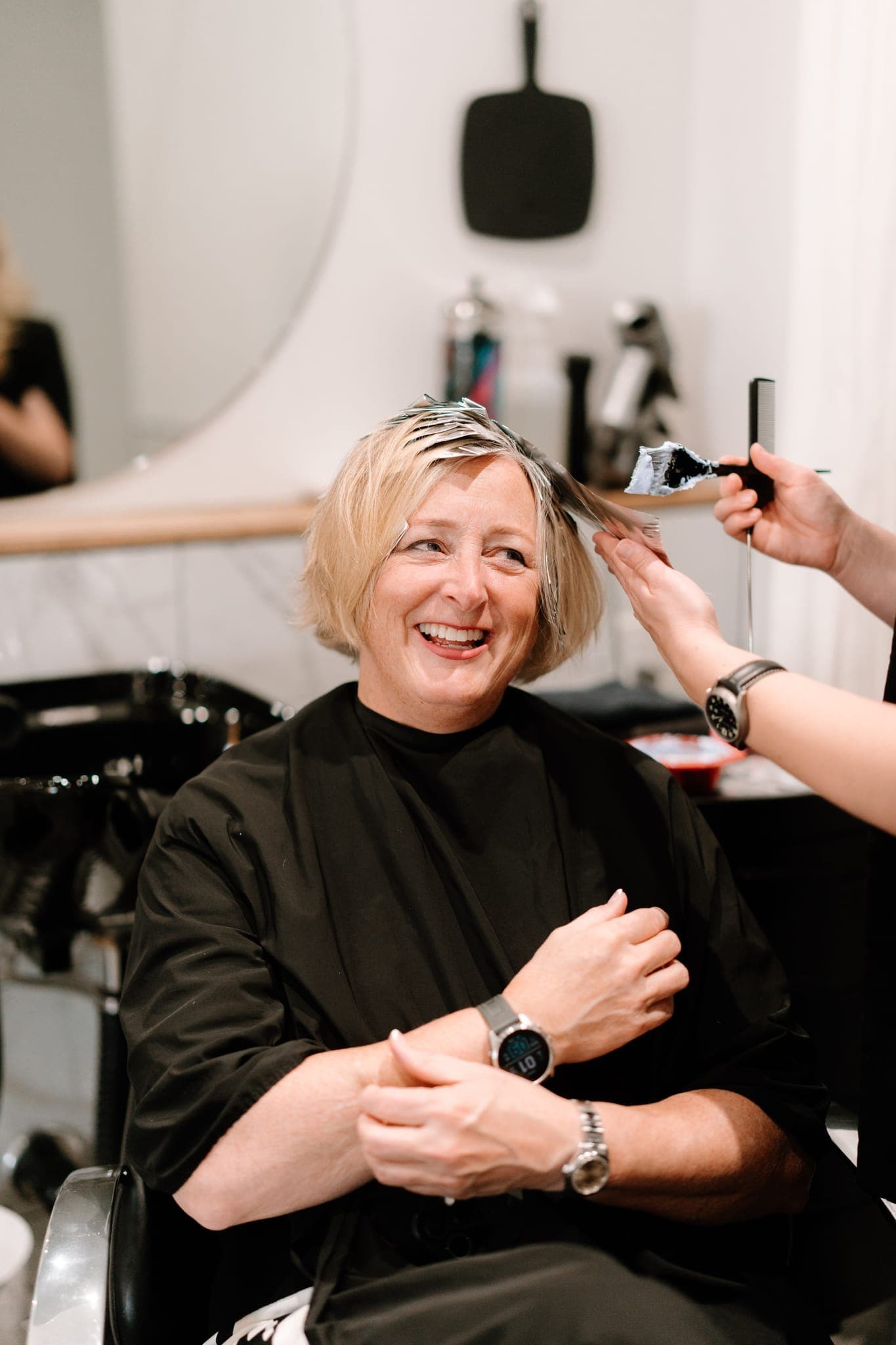 Smiling client having colour applied during a visit to Lustre of Pearl