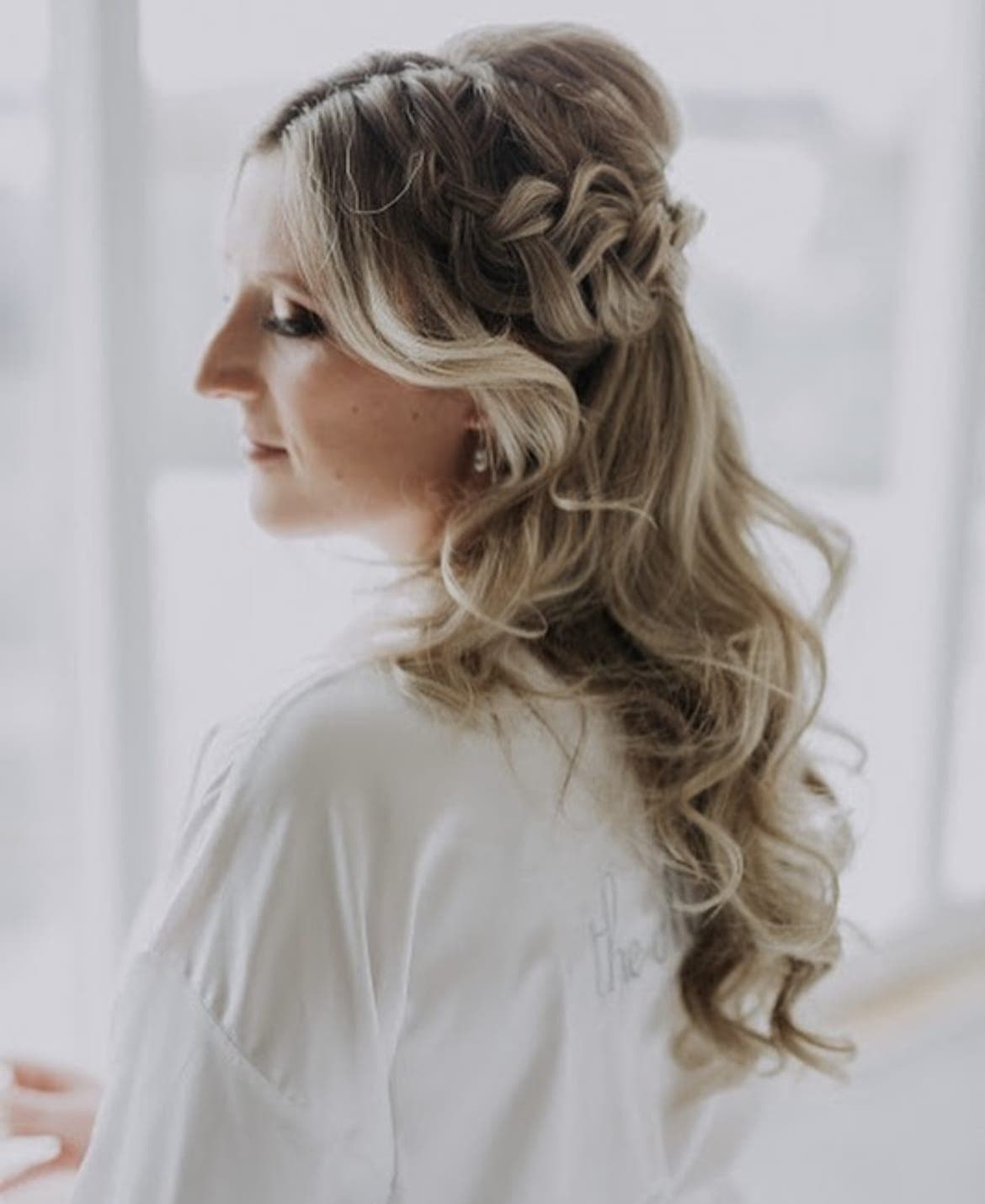 Profile of a bride with a braided half-up style and long blonde curls