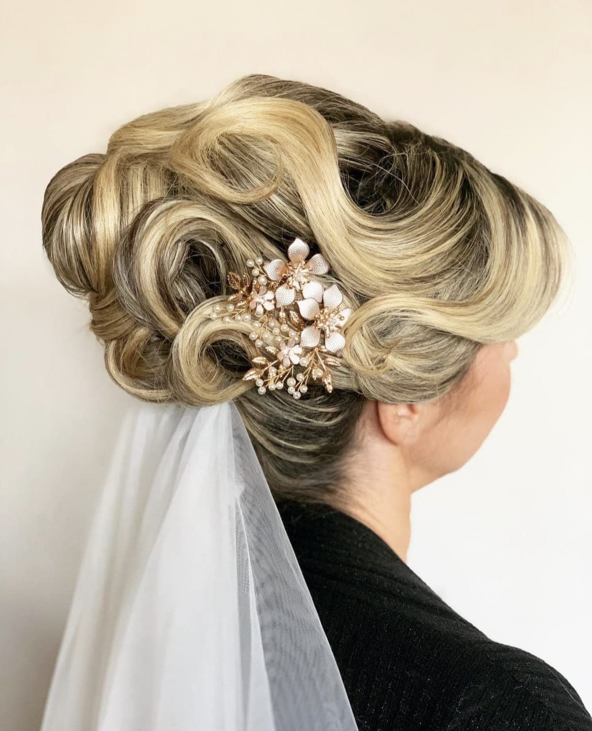 Sculpted blonde vintage-wave updo with a floral comb and veil