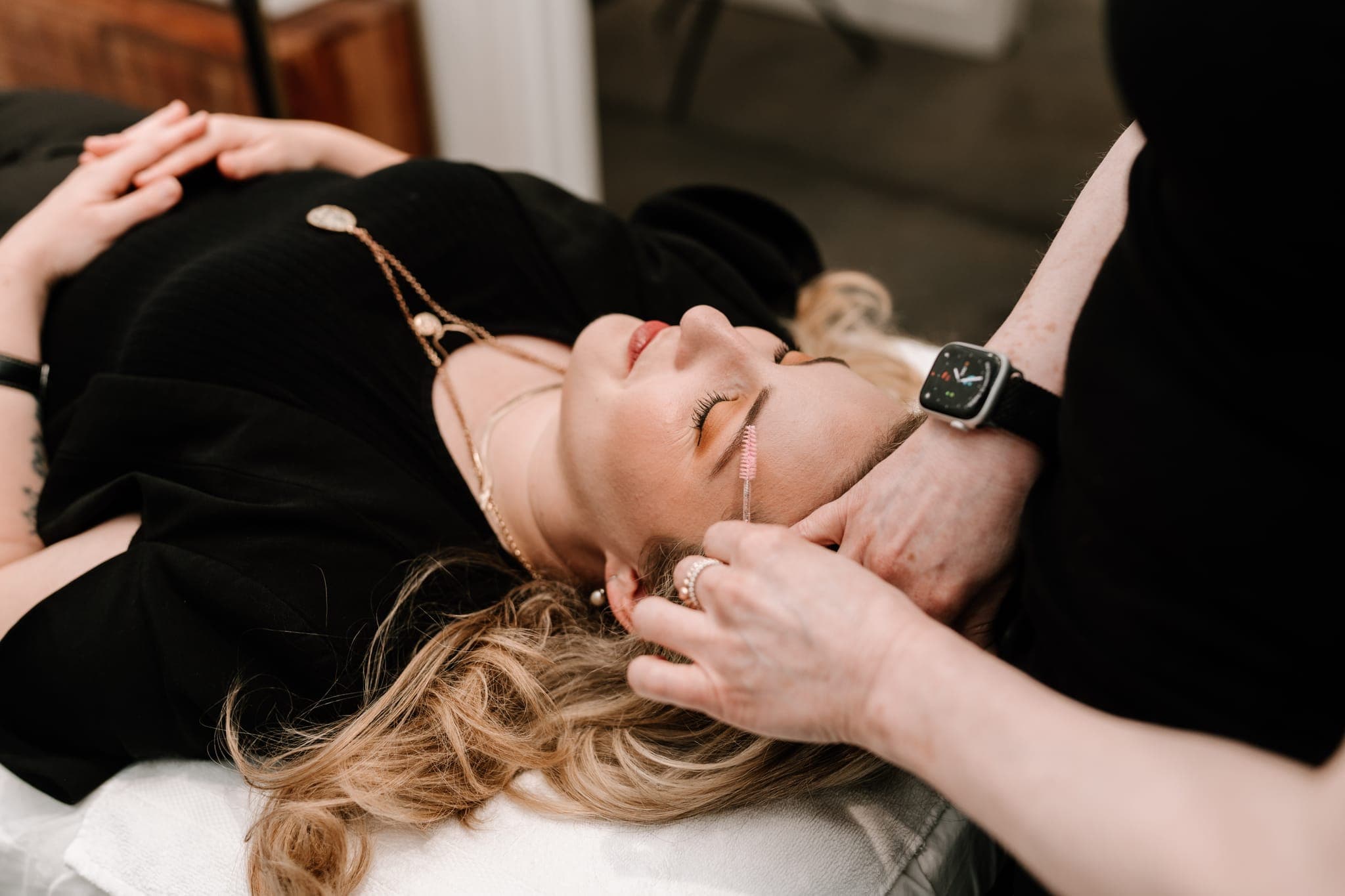 Close-up of a spoolie brush grooming a client’s brow
