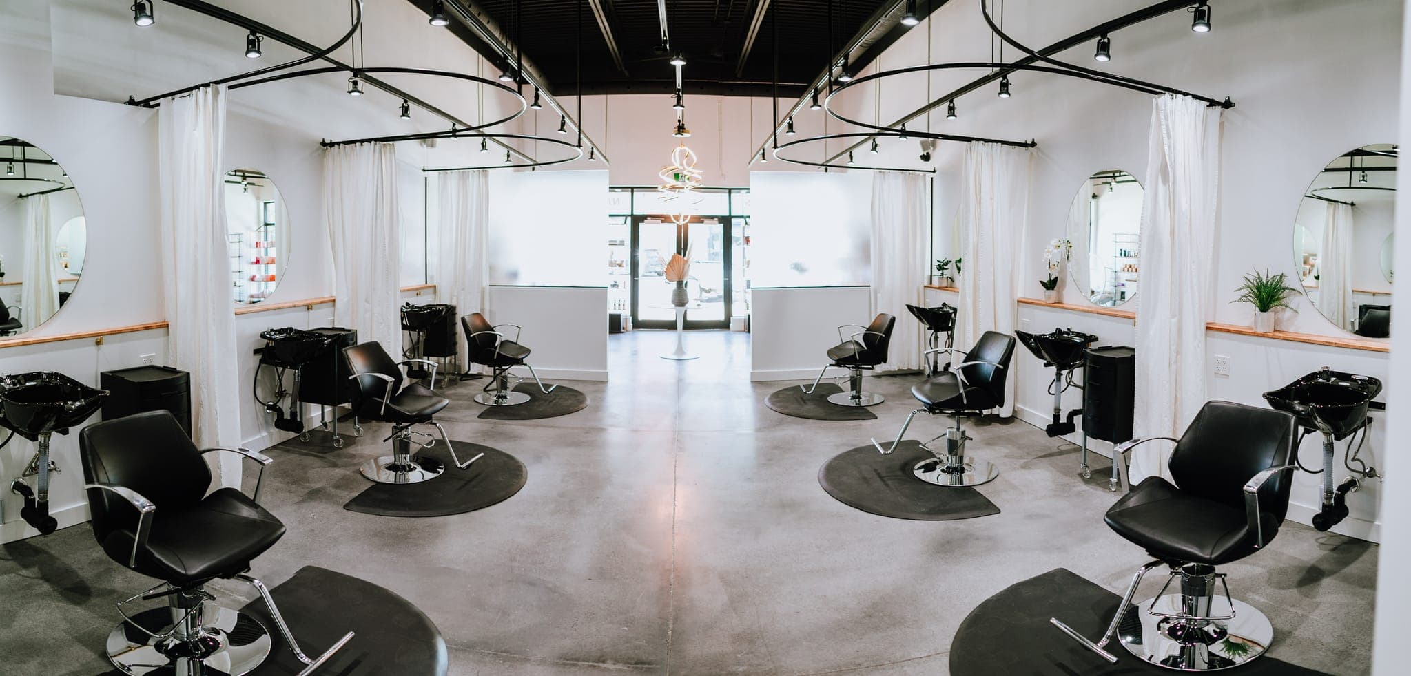 Wide view of the Lustre of Pearl salon floor with styling chairs and round mirrors