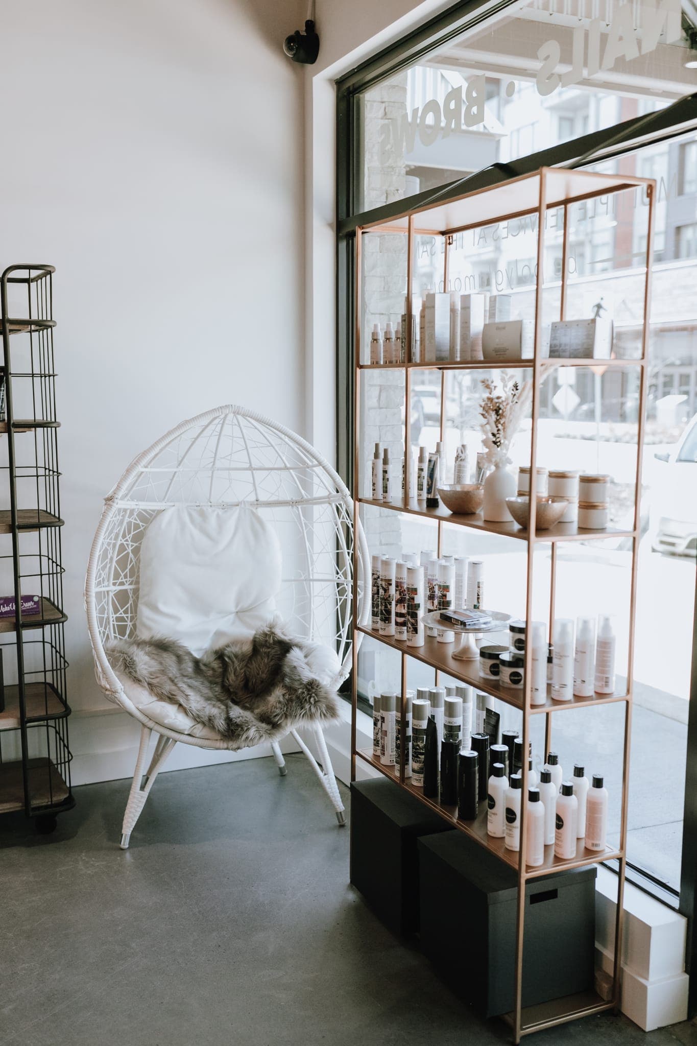 Retail product shelving beside the white egg chair by the front window