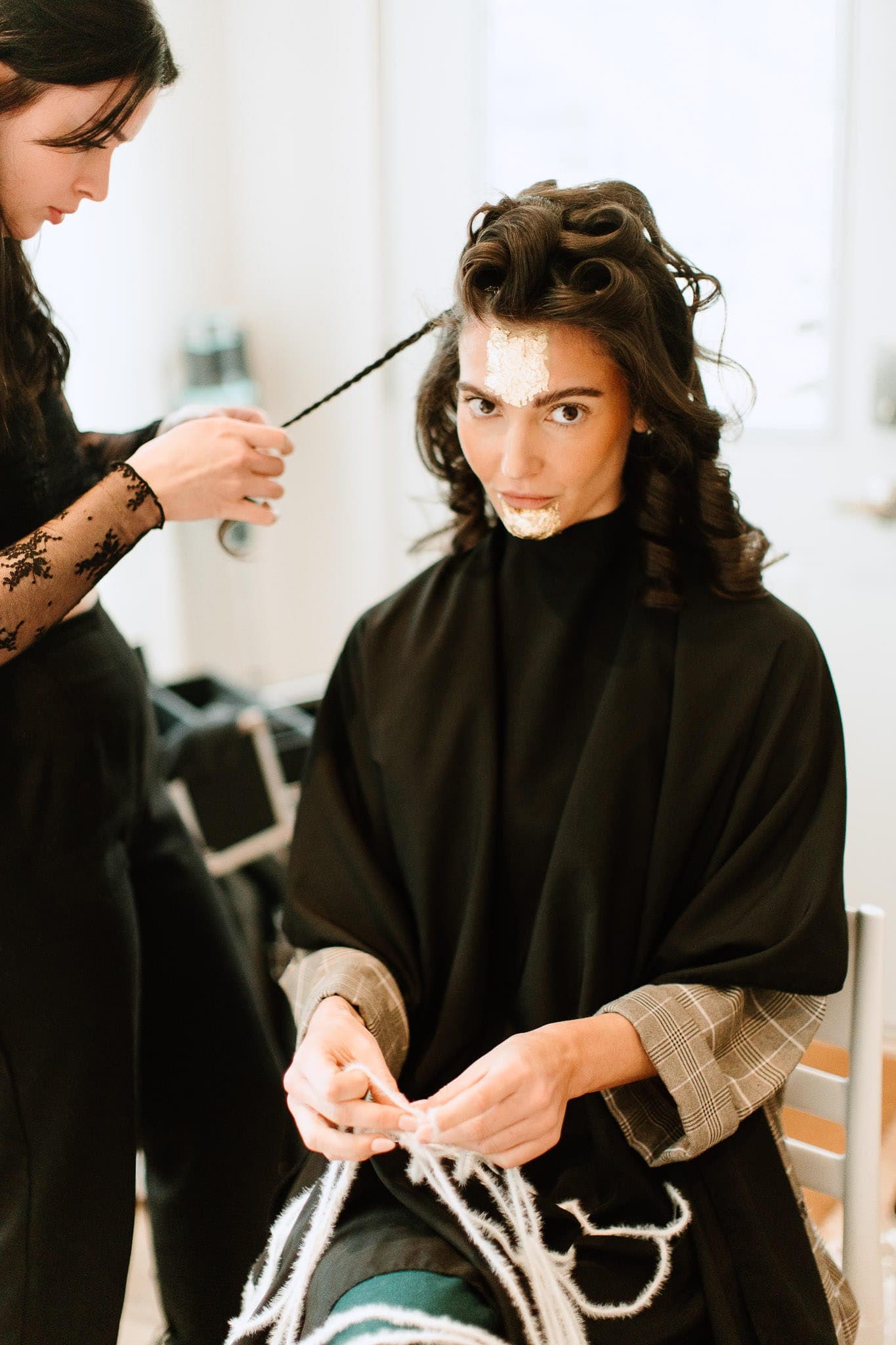 Stylist curling a client’s long dark hair at Lustre of Pearl