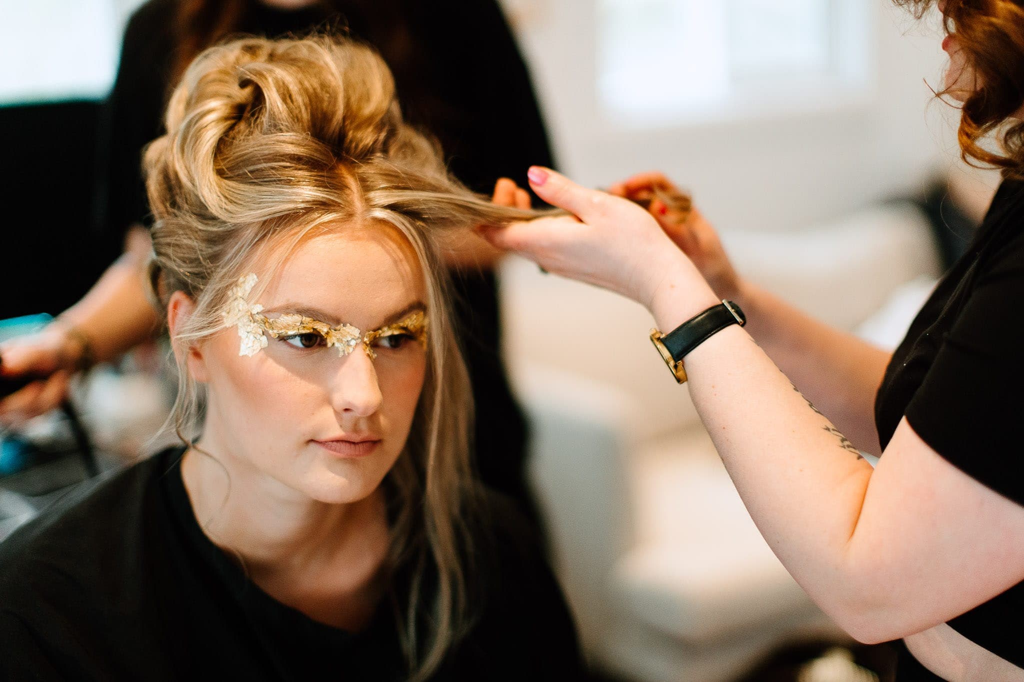 Stylist shaping a voluminous blonde updo