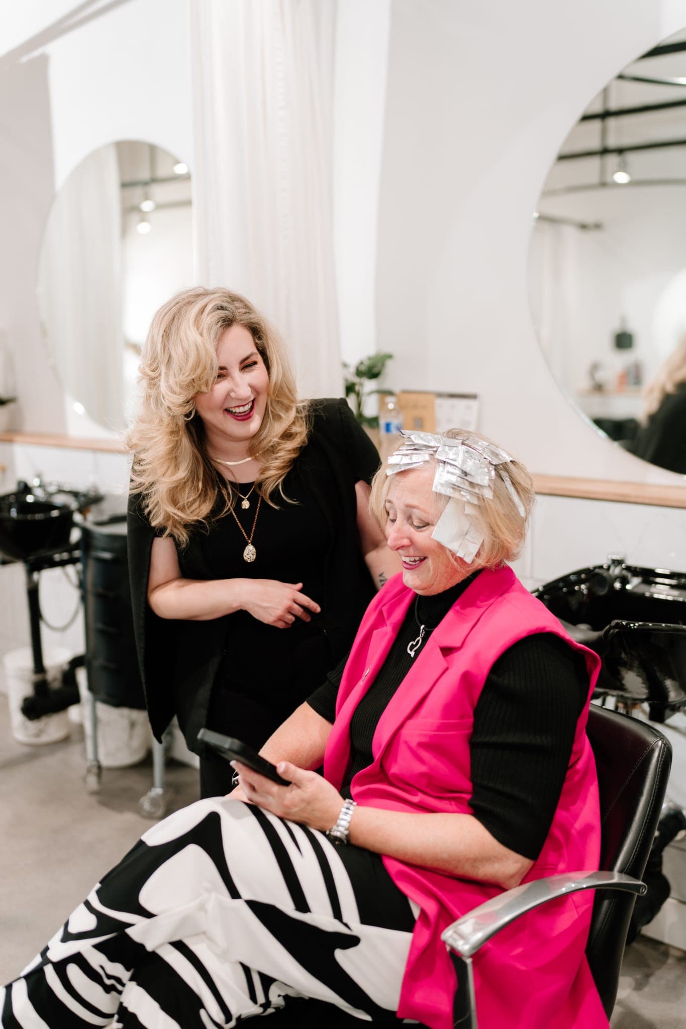 Stylist and client laughing during a colour service