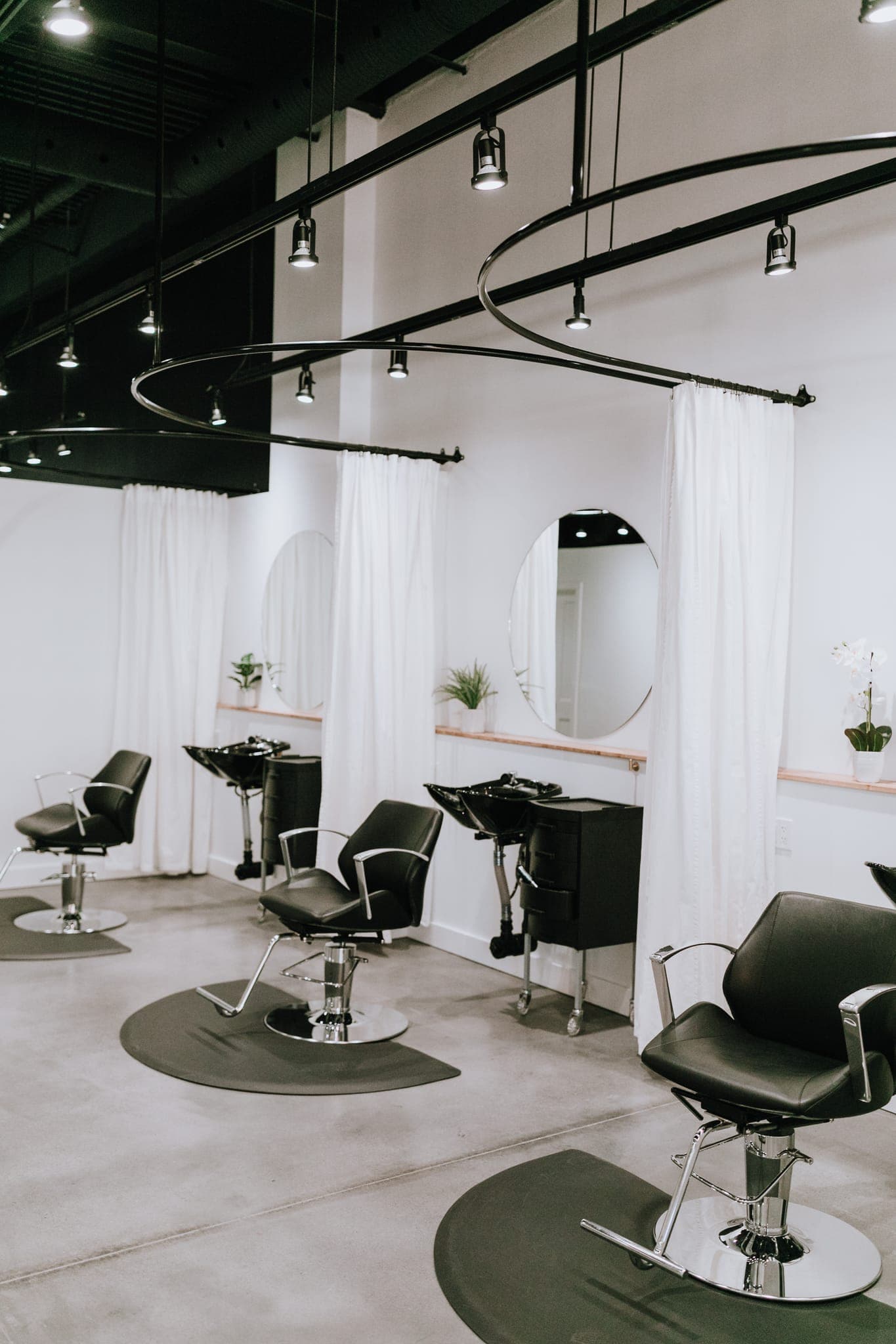 Salon styling area with round mirrors and sheer curtains