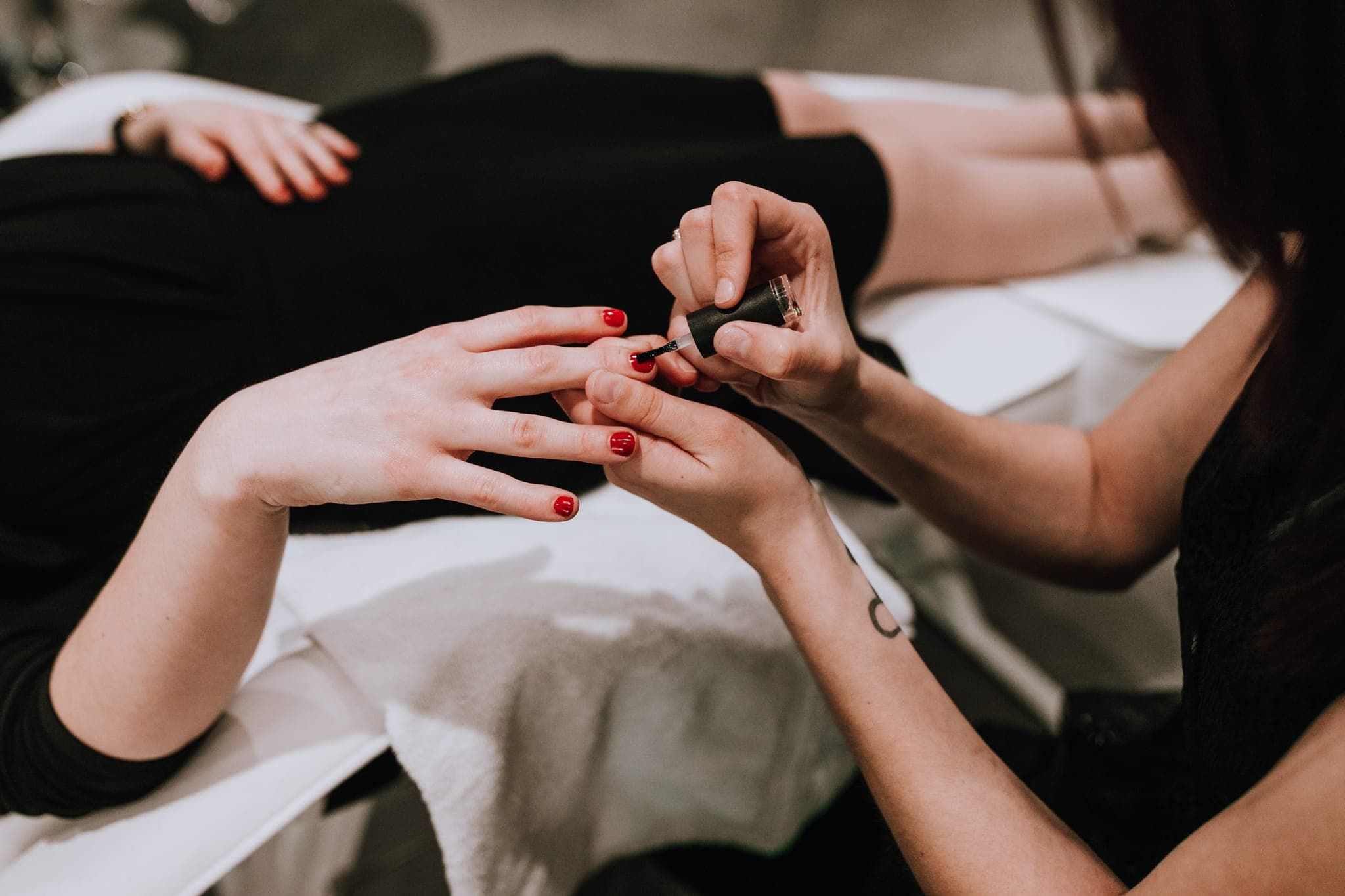 Manicurist applying red polish during a manicure at Lustre of Pearl