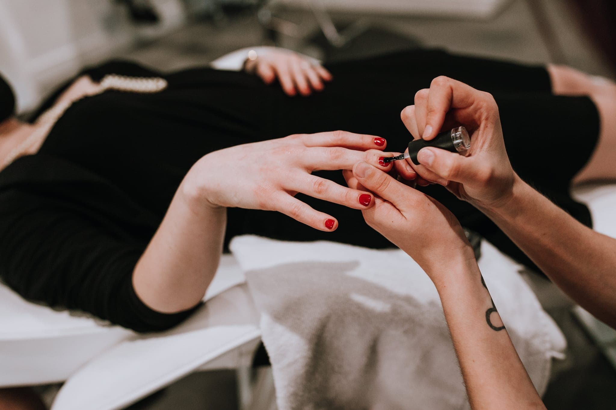 Close-up of red nail polish being applied to a client’s hand